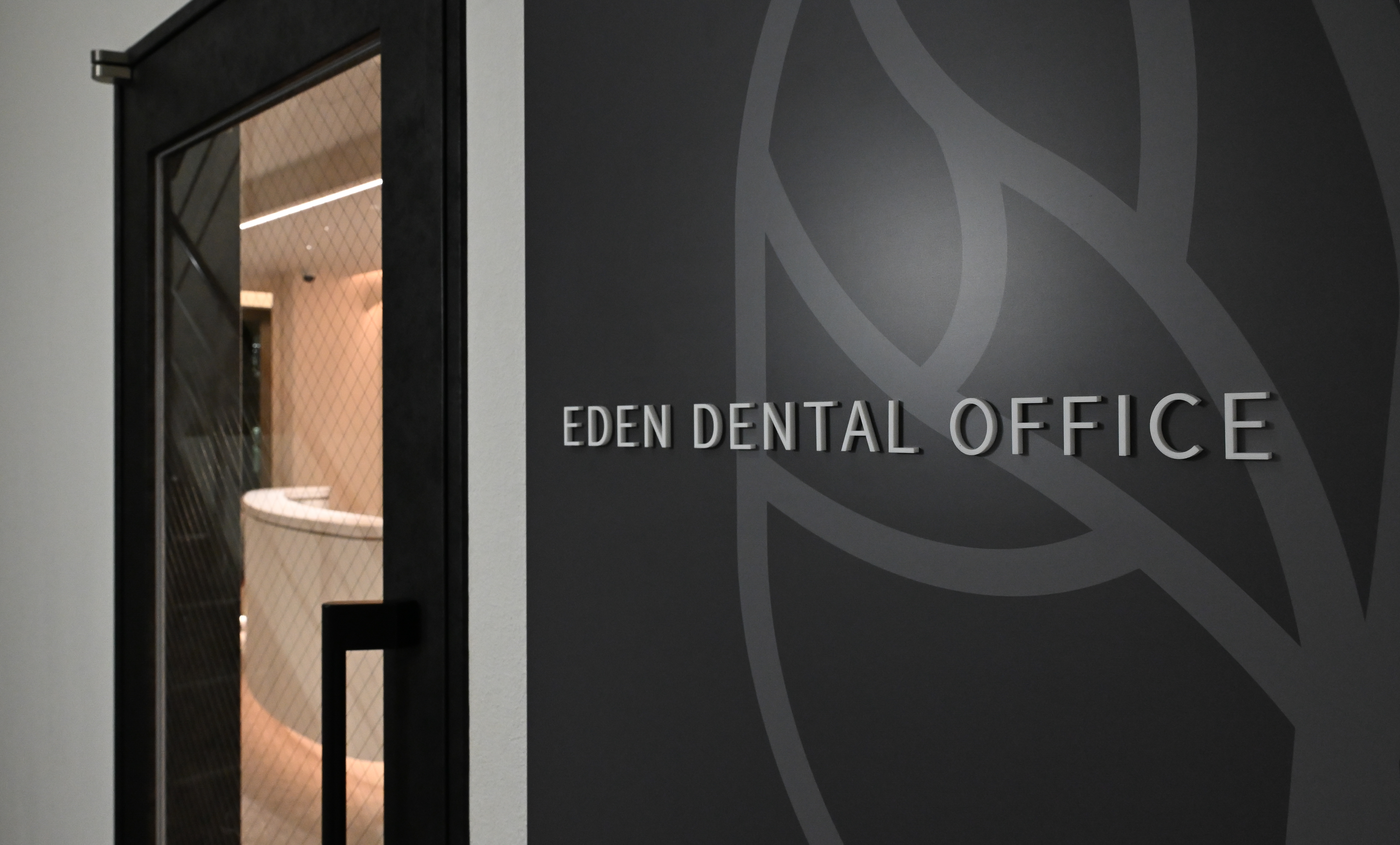 Eden Dental Office entrance on the 4th floor with logo on dark wall